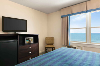 hotel room showing bed, tv, and windows
